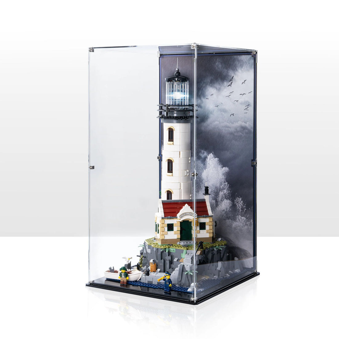 LEGO Motorised Lighthouse 21335 and its island inside a tall clear display case with a coastal background